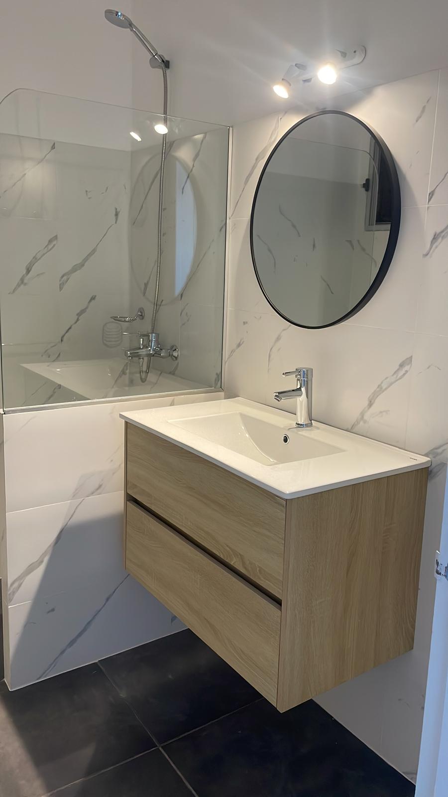 Detalle de terminaciones del baño renovado: espejo redondo y vanitory